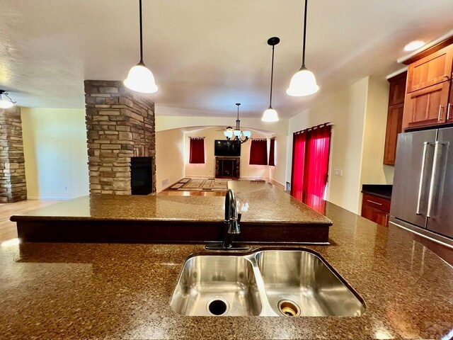 kitchen featuring a fireplace, open floor plan, a sink, and decorative light fixtures