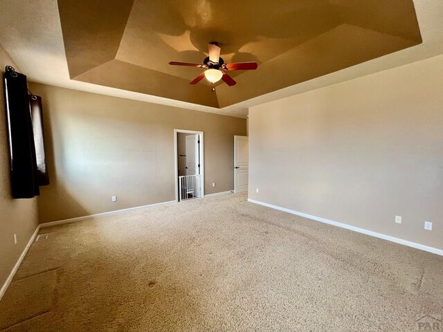 spare room with baseboards, a tray ceiling, and carpet flooring