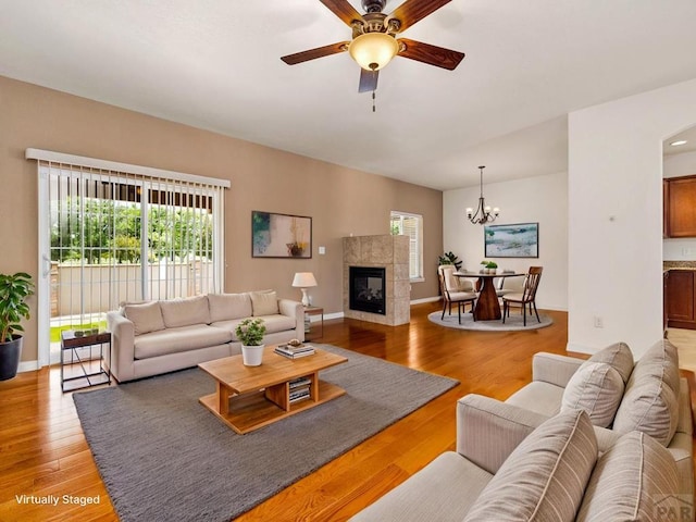 5522 Ventana Ct, Pueblo, CO 81005 - living room with light wood-style flooring, a ceiling fan, a chandelier, and a tiled fireplace