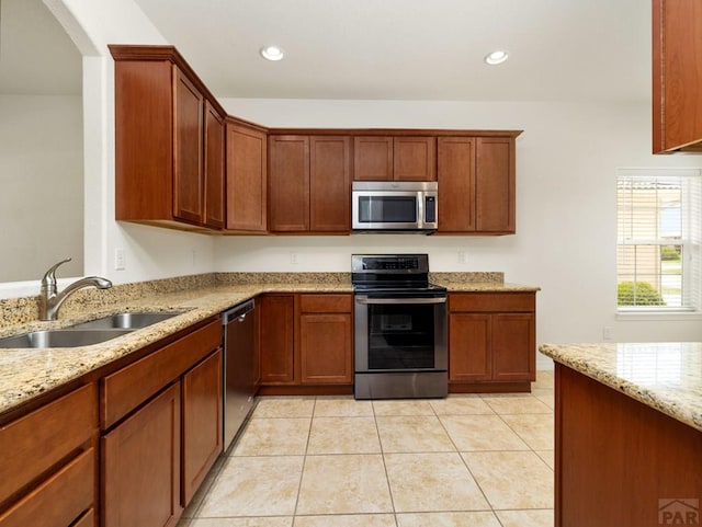 5522 Ventana Ct, Pueblo, CO 81005 - kitchen featuring appliances with stainless steel finishes, light stone countertops, light tile patterned floors, recessed lighting, and brown cabinets
