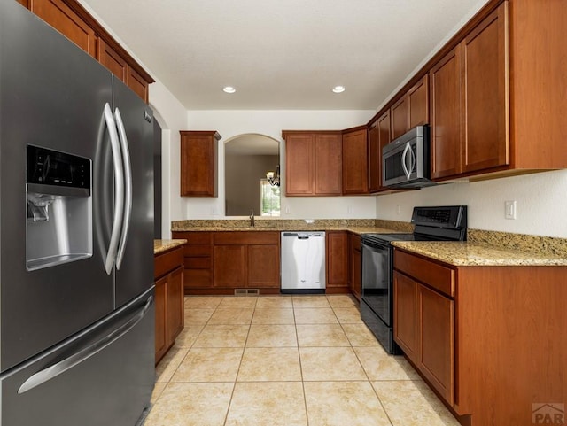 5522 Ventana Ct, Pueblo, CO 81005 - kitchen featuring appliances with stainless steel finishes, arched walkways, light tile patterned floors, recessed lighting, and brown cabinetry
