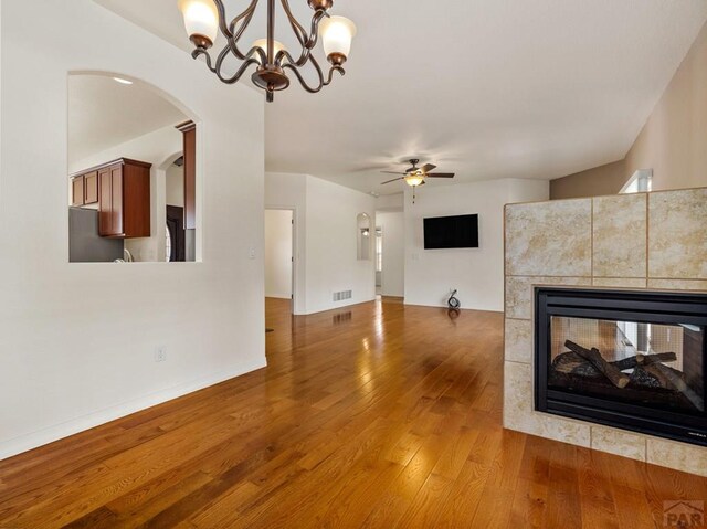 5522 Ventana Ct, Pueblo, CO 81005 - unfurnished living room with a ceiling fan, hardwood / wood-style floors, a tile fireplace, a chandelier, and arched walkways