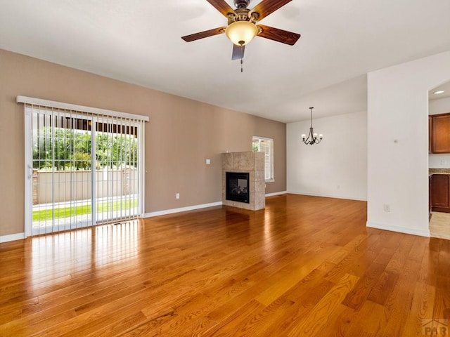 5522 Ventana Ct, Pueblo, CO 81005 - unfurnished living room with light wood-style floors, a chandelier, a tile fireplace, and a ceiling fan