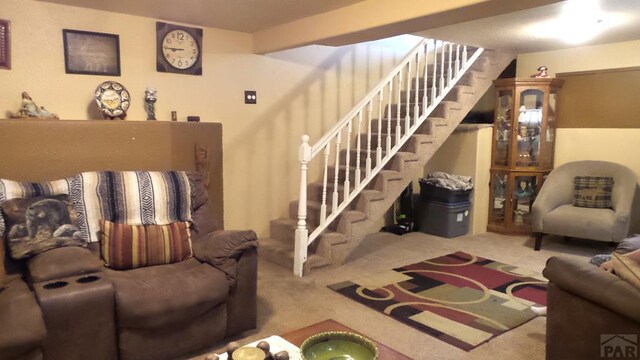 carpeted living room with beamed ceiling and stairway