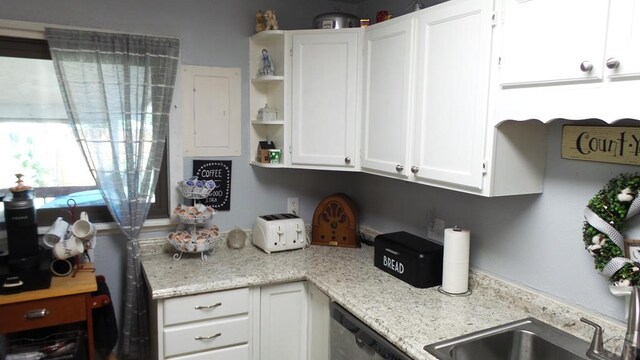 kitchen with dishwashing machine, light stone countertops, white cabinetry, and open shelves