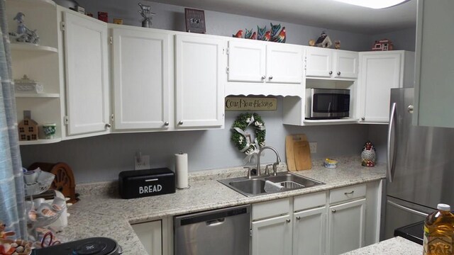 kitchen with appliances with stainless steel finishes, white cabinets, a sink, and open shelves