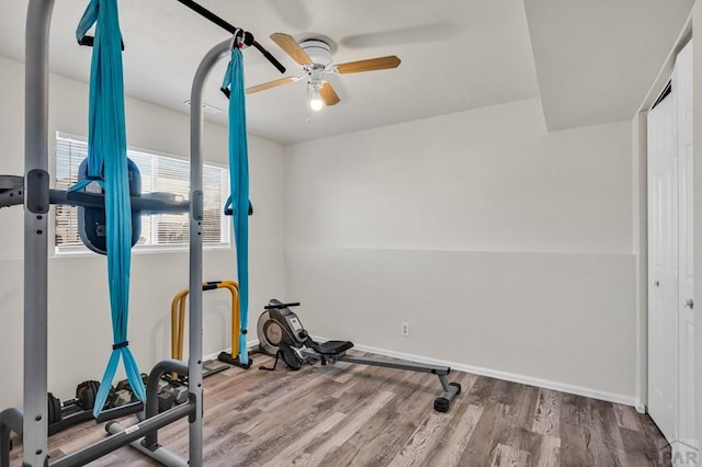 workout area with light wood finished floors, baseboards, and a ceiling fan