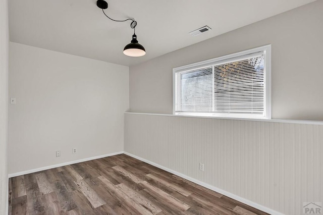 spare room with baseboards, visible vents, and dark wood-type flooring