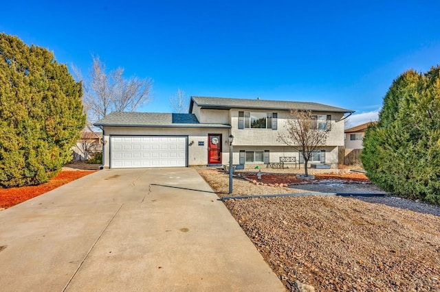 split level home with concrete driveway, an attached garage, and stucco siding