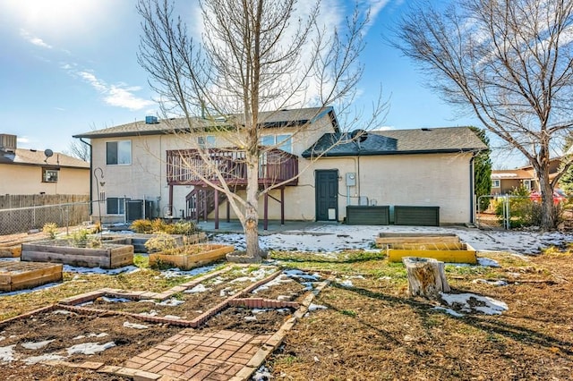 back of house with a garden, fence, and stucco siding