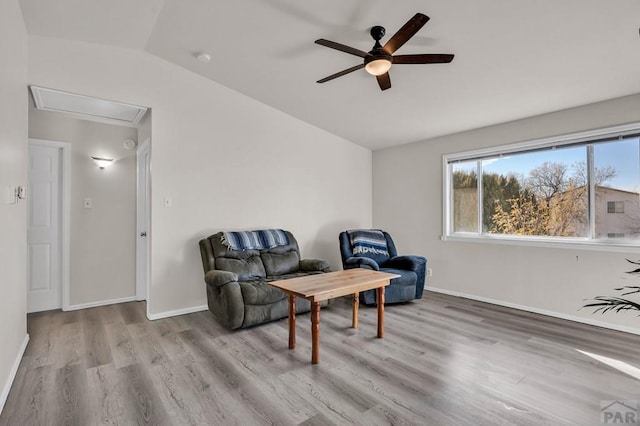 living area featuring a ceiling fan, lofted ceiling, light wood-style flooring, and baseboards