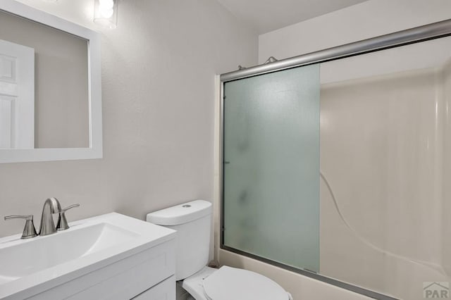 bathroom featuring enclosed tub / shower combo, vanity, and toilet