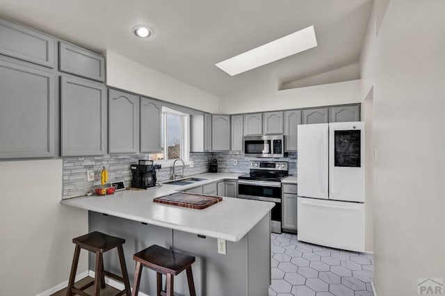 kitchen with a peninsula, appliances with stainless steel finishes, light countertops, and a breakfast bar area