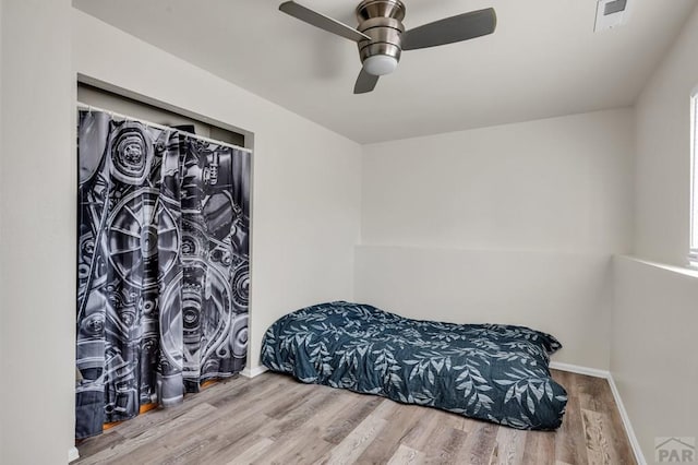 bedroom featuring a ceiling fan, visible vents, baseboards, and wood finished floors