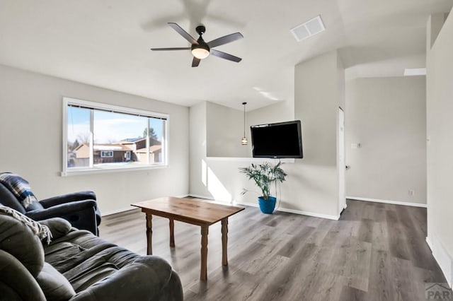 living room featuring a ceiling fan, visible vents, baseboards, and wood finished floors