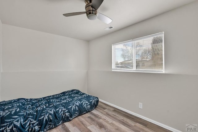 bedroom with visible vents, ceiling fan, baseboards, and wood finished floors