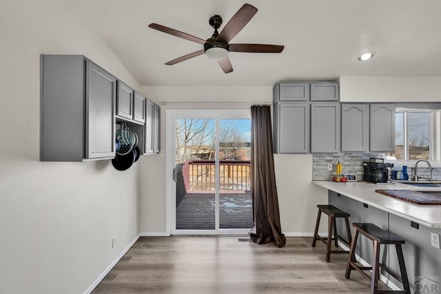 kitchen with gray cabinetry, light countertops, tasteful backsplash, and a kitchen breakfast bar