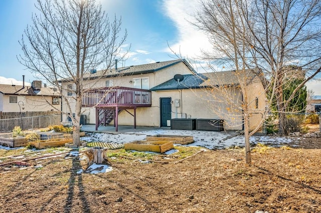 back of house with a vegetable garden, stucco siding, stairway, fence, and a deck