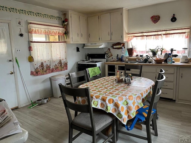 kitchen featuring light wood finished floors, gas stove, and under cabinet range hood