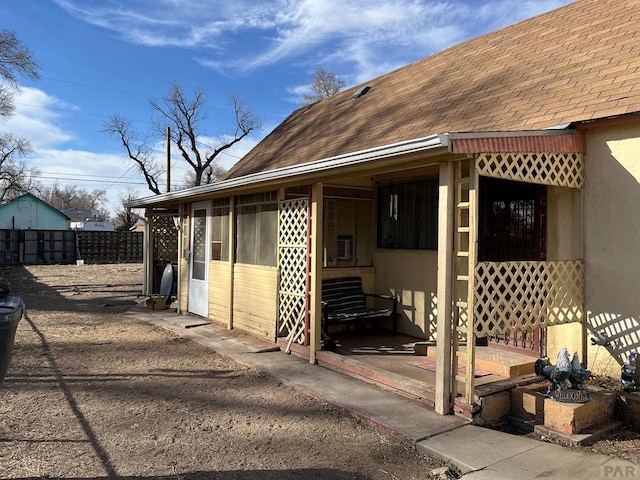 exterior space with a shingled roof, fence, and a sunroom