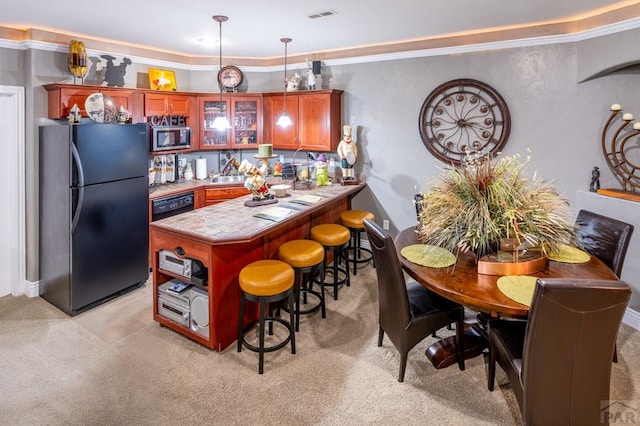 1700 Aquila Dr, Pueblo, CO 81008 - kitchen with black appliances, light carpet, a kitchen bar, glass insert cabinets, and crown molding