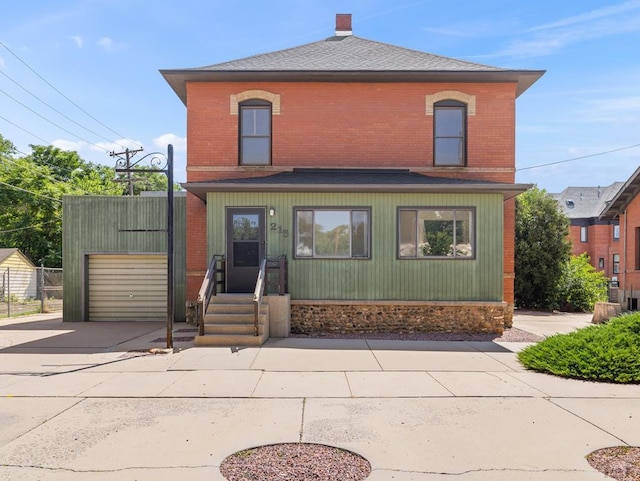 215 E Pitkin Ave, Pueblo, CO 81004 - view of front of property with concrete driveway, brick siding, a garage, and roof with shingles