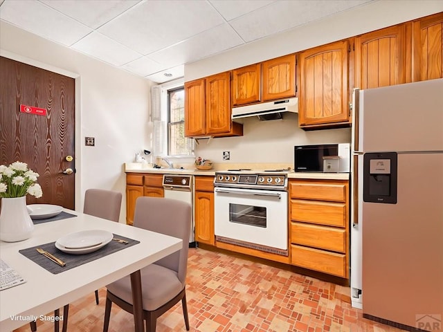 215 E Pitkin Ave, Pueblo, CO 81004 - kitchen featuring white appliances, under cabinet range hood, light countertops, and brown cabinetry