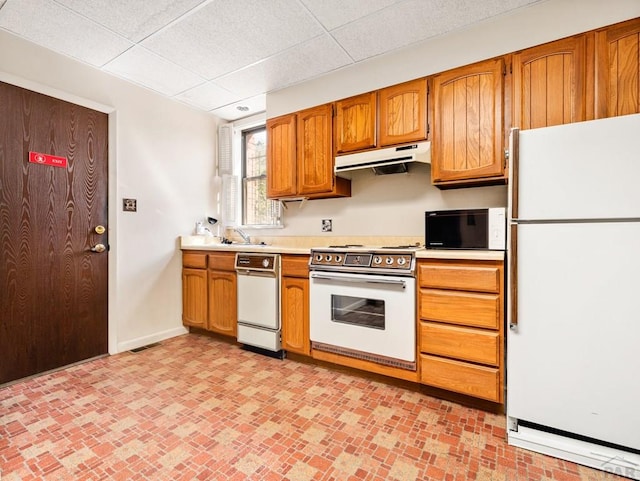 215 E Pitkin Ave, Pueblo, CO 81004 - kitchen with white appliances, under cabinet range hood, light countertops, a paneled ceiling, and brown cabinets