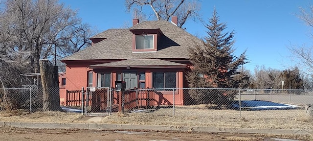 view of front facade featuring a fenced front yard, roof with shingles, and brick siding