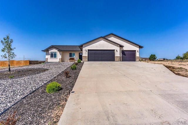 1207 N Jon Ln, Pueblo West, CO 81007 - single story home featuring stucco siding, a garage, driveway, and stone siding