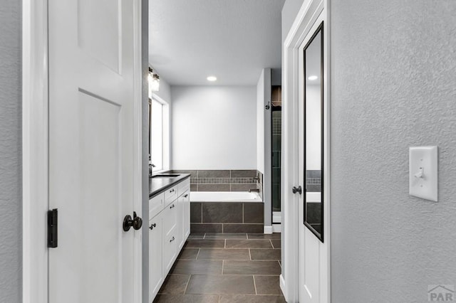 1207 N Jon Ln, Pueblo West, CO 81007 - bathroom featuring a garden tub, vanity, a textured wall, recessed lighting, and tile patterned floors