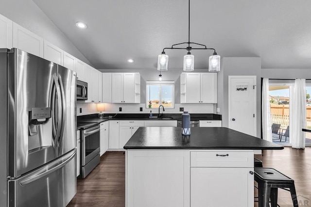 1207 N Jon Ln, Pueblo West, CO 81007 - kitchen featuring stainless steel appliances, dark countertops, dark wood-style floors, white cabinetry, and vaulted ceiling