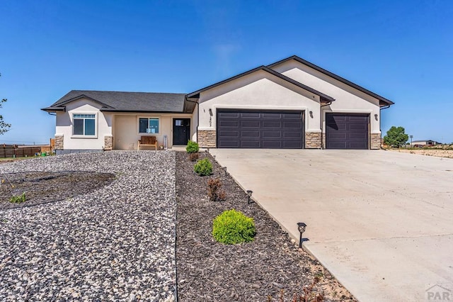 1207 N Jon Ln, Pueblo West, CO 81007 - ranch-style home featuring stucco siding, stone siding, a garage, and driveway