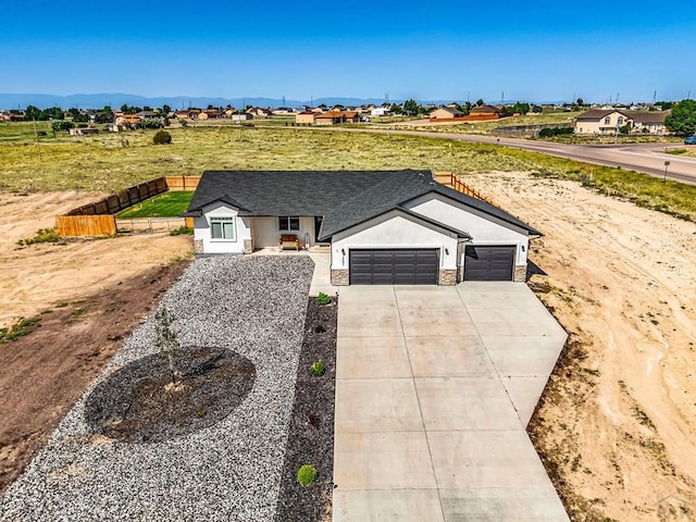1207 N Jon Ln, Pueblo West, CO 81007 - ranch-style home featuring a garage, concrete driveway, stucco siding, a shingled roof, and a mountain view