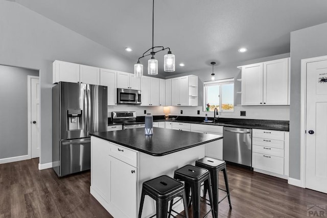 1207 N Jon Ln, Pueblo West, CO 81007 - kitchen with stainless steel appliances, dark countertops, open shelves, white cabinetry, and a kitchen island