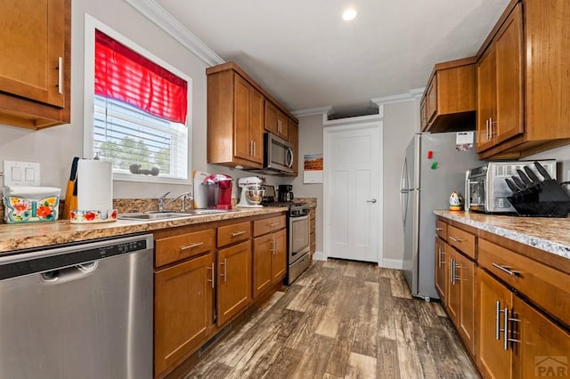 999 Fortino Blvd Unit 237, Pueblo, CO 81008 - kitchen featuring stainless steel appliances, brown cabinetry, ornamental molding, dark wood-style flooring, and a sink