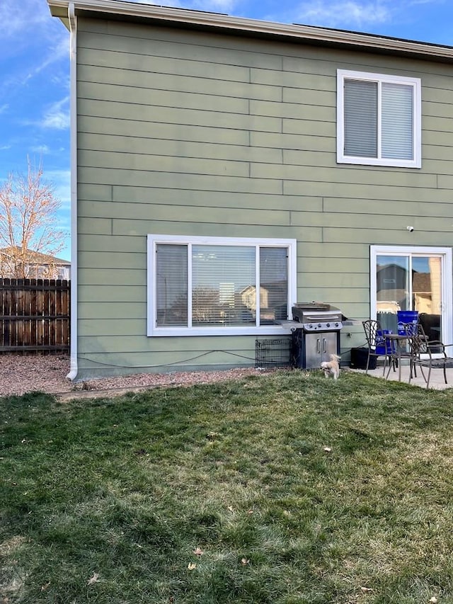back of house featuring fence, a patio area, and a lawn