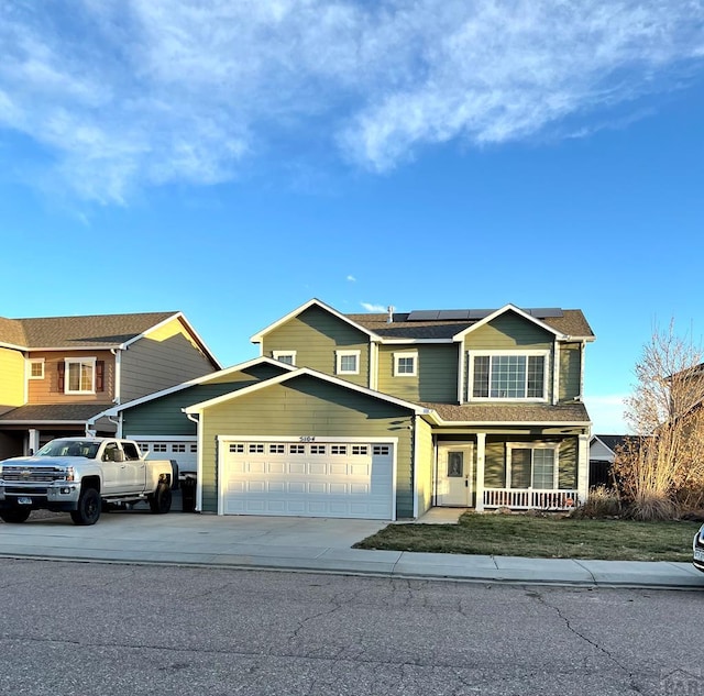 view of front facade with a garage, covered porch, solar panels, and concrete driveway