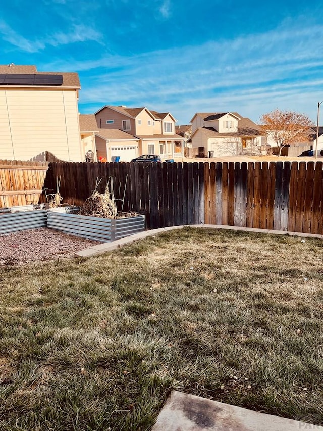 view of yard featuring a fenced backyard, a garden, and a residential view