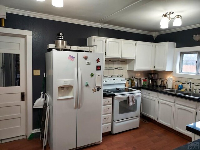 kitchen with white appliances, dark countertops, a sink, and white cabinets