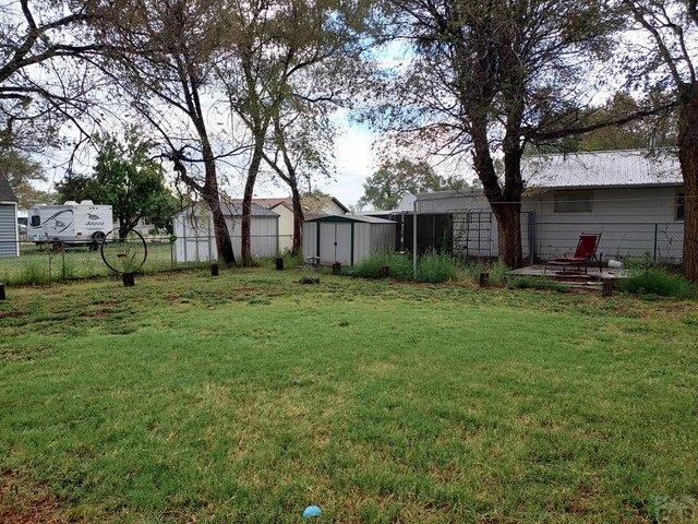 view of yard featuring an outbuilding, a shed, and fence