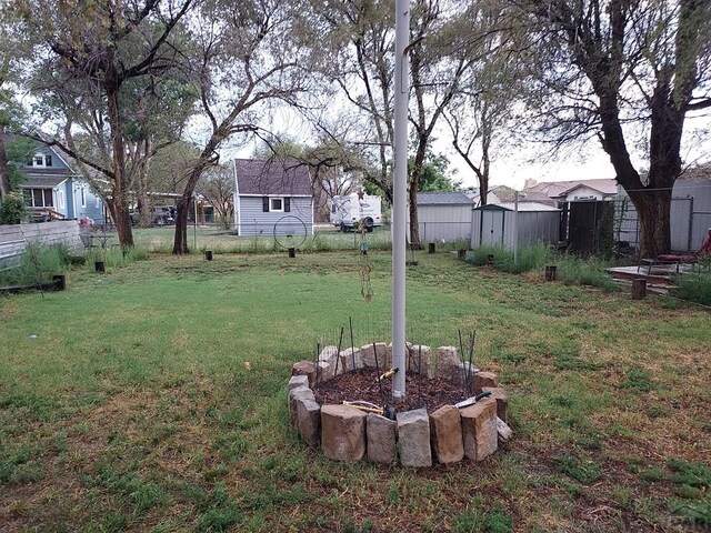 view of yard featuring a storage shed, an outdoor structure, fence, and a residential view