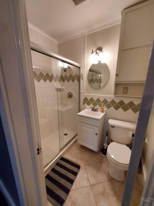 bathroom featuring tile walls, toilet, ornamental molding, a shower stall, and vanity