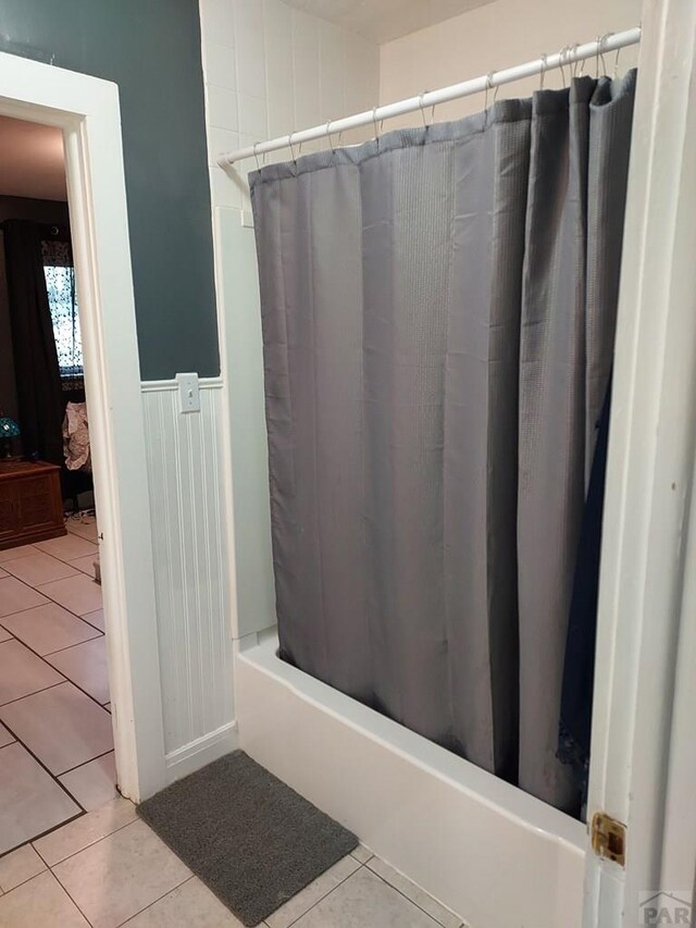 bathroom with wainscoting, tile patterned flooring, and shower / bathtub combination with curtain