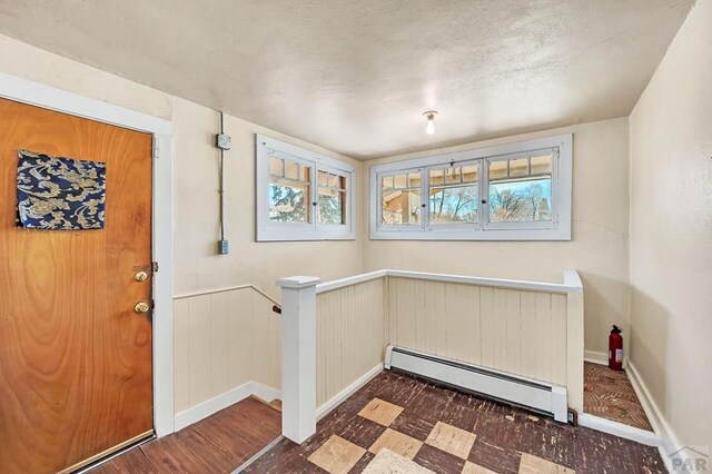 interior space with dark floors, baseboards, plenty of natural light, and baseboard heating