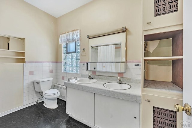 bathroom featuring radiator, double vanity, tile walls, and a sink