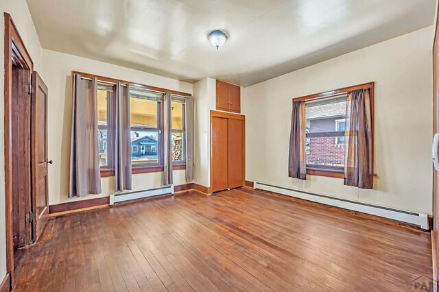 spare room featuring baseboard heating and wood finished floors