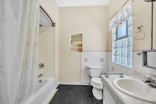 full bath featuring toilet, vanity, tile walls, wainscoting, and shower / bath combo