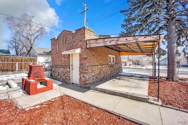 view of side of property featuring stone siding, brick siding, fence, and driveway