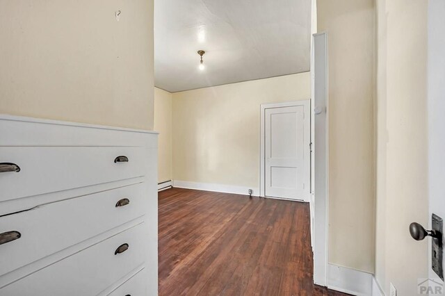 interior space featuring baseboard heating, dark wood finished floors, and baseboards